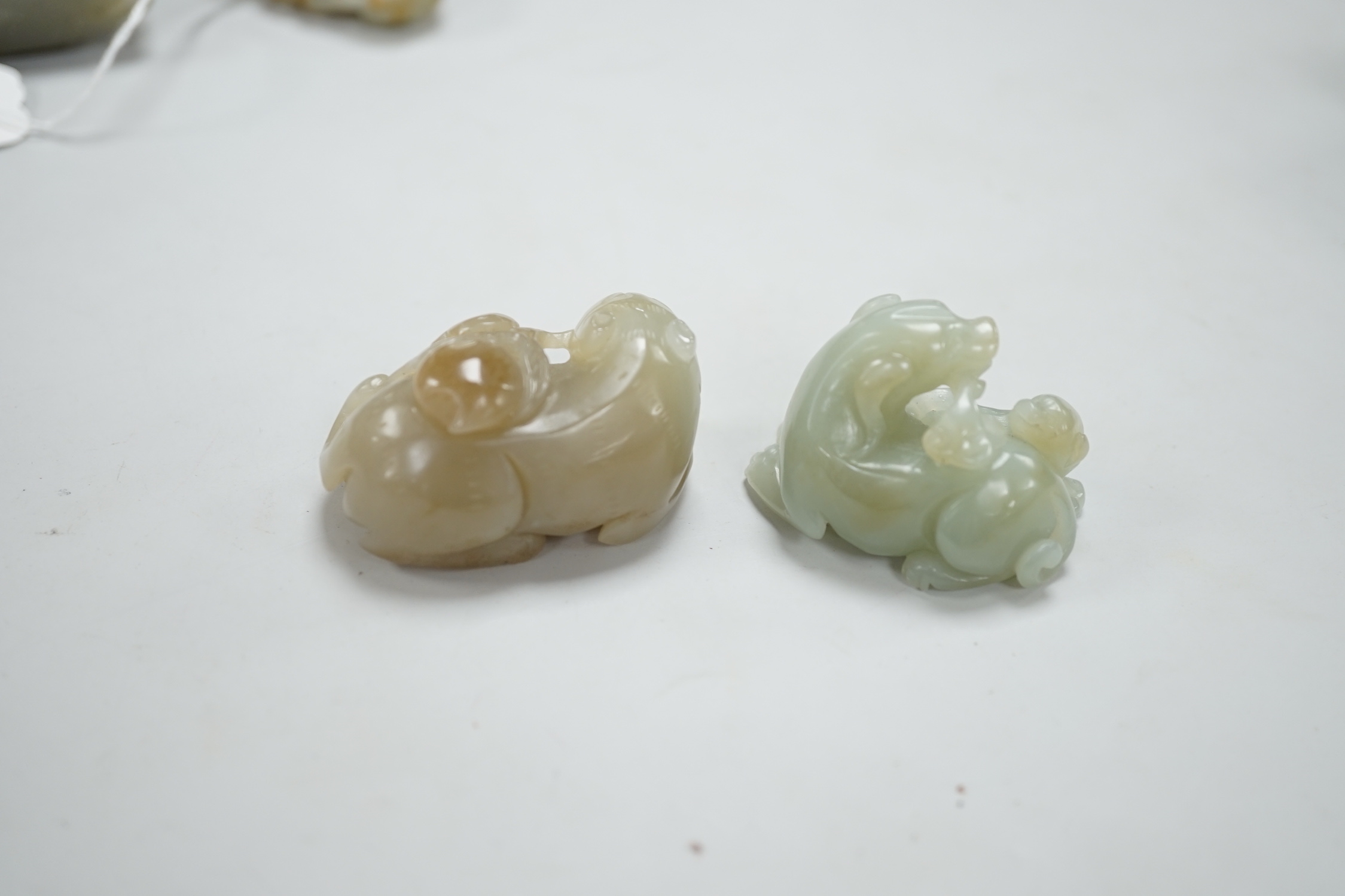 A Chinese celadon and brown jade figure of a cat biting a peach branch and a celadon jade group of a dog and puppy, cat biting a peach branch 5cm wide (2)